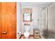 Bathroom features a toilet, storage cabinet, a window with floral valance, and a glass enclosed tile shower at 2435 Farmer Road, Conyers, GA 30012