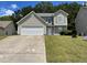 Charming two-story home featuring a well-maintained lawn and a concrete driveway leading to an attached two-car garage at 1421 Isleworth Cir, College Park, GA 30349