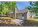 A view of the backyard featuring green trees, grass, neutral siding, windows, and a concrete patio at 1363 To Lani Farm Rd, Stone Mountain, GA 30083