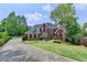Stately brick home featuring a well-manicured lawn and circular driveway at 320 Chason Wood Way, Roswell, GA 30076