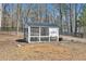 White wooden chicken coop in a wooded setting with a fenced perimeter at 1455 Rucker Cir, Woodstock, GA 30188
