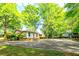 Quaint cottage-style home surrounded by lush greenery and a spacious driveway at 1098 Cown Rd, Villa Rica, GA 30180