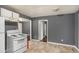 View of kitchen with white appliances, neutral backsplash, light floors, and a view into another room at 2412 Forrest Park Se Rd, Atlanta, GA 30315