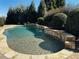 An inviting backyard pool features a stone waterfall and mature landscaping at 216 Slate Dr, Buford, GA 30518