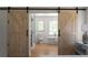 Bright bathroom beyond sliding barn doors features hardwood floors, a standalone tub, and modern fixtures at 3984 Earney Rd, Woodstock, GA 30188