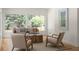 Cozy living room with a large window offering views of mature trees, neutral furniture, and wood floors at 3984 Earney Rd, Woodstock, GA 30188