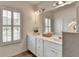 Bright bathroom with white cabinets, double sinks, large mirror, and plantation shutters on the window at 3677 Sorrel Ln, Duluth, GA 30096