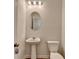 Elegant half bathroom featuring a pedestal sink, oval mirror, and sleek lighting fixture at 3677 Sorrel Ln, Duluth, GA 30096