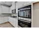 Close up of modern kitchen featuring white cabinets, granite counters and stainless double ovens at 3677 Sorrel Ln, Duluth, GA 30096