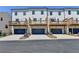 Rear exterior of townhomes featuring private decks above garages with paved driveway at 3677 Sorrel Ln, Duluth, GA 30096