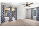 This bedroom has carpet, a ceiling fan, curtains, and sliding glass door to screened porch at 8083 Cypress Ct, Villa Rica, GA 30180