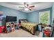 Blue bedroom with ceiling fan, large window and a bed with a green comforter at 3215 Rose Petal Ln, Powder Springs, GA 30127