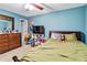 Bright bedroom features a bed with a green comforter, a dresser and sky blue walls at 3215 Rose Petal Ln, Powder Springs, GA 30127
