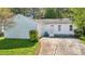 Charming white home featuring a cracked driveway and a small front yard with greenery at 2058 Corners Cir, Lithonia, GA 30058