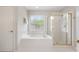 Well-lit bathroom with a soaking tub, glass shower, white tile, and natural light from a window at 2263 Seatton Ct, Marietta, GA 30062