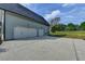 Three car garage featuring white doors, exterior lighting and concrete driveway at 86 Ewing Way, Dacula, GA 30019