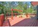 Wide angle view of a red stained wooden back deck with a pergola in a wooded back yard at 225 Bayswater Dr, Suwanee, GA 30024