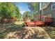 Backyard featuring a red deck, a pergola, and a well-maintained lawn surrounded by mature trees at 225 Bayswater Dr, Suwanee, GA 30024