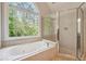 Bathroom with a luxurious soaking tub under a window and a glass door shower at 225 Bayswater Dr, Suwanee, GA 30024