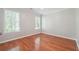 Bedroom featuring two windows for natural light, hardwood floors, and neutral walls and trim at 225 Bayswater Dr, Suwanee, GA 30024
