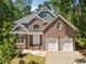 Traditional brick home featuring an attached two-car garage and professionally landscaped front yard at 225 Bayswater Dr, Suwanee, GA 30024