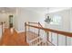 Hallway featuring hardwood floors, a chandelier, white painted banisters, and arched window above entry at 225 Bayswater Dr, Suwanee, GA 30024