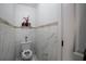 Powder room with marble tile walls, toilet, and dark fixtures at 3770 Falling Leaf Ln, Cumming, GA 30041