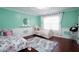 Inviting bedroom featuring mint walls, white trim, hardwood floors, and two cozy floral-themed beds at 3770 Falling Leaf Ln, Cumming, GA 30041