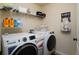 Efficient laundry room with modern washer and dryer, shelving, and a ' and ' sign at 3770 Falling Leaf Ln, Cumming, GA 30041