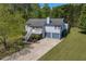 View of two-story home with gray siding and stone accents, complemented by lush trees and a driveway at 582 Linda Ln, Powder Springs, GA 30127