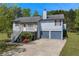 Two-story house featuring gray siding, stone accents, a cozy balcony, and a two-car garage on a sunny day at 582 Linda Ln, Powder Springs, GA 30127
