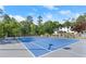 Beautiful blue and grey backyard tennis court surrounded by lush green trees and modern lighting at 4440 Webb Bridge Rd, Alpharetta, GA 30005