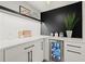 Modern wet bar featuring a white countertop, black backsplash, built-in mini-fridge, and sleek cabinetry at 4440 Webb Bridge Rd, Alpharetta, GA 30005