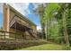 Back exterior of home featuring a two level deck, stone retaining wall, and lush trees at 2895 Shurburne Dr, Alpharetta, GA 30022