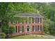 Classic brick home with black shutters and a well-manicured lawn surrounded by mature trees at 2895 Shurburne Dr, Alpharetta, GA 30022