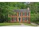 Charming two-story brick home with black shutters surrounded by lush landscaping at 2895 Shurburne Dr, Alpharetta, GA 30022