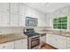 This bright kitchen features stainless steel appliances, stone countertops, and plenty of white cabinetry at 2895 Shurburne Dr, Alpharetta, GA 30022