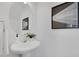 Clean bathroom featuring a white pedestal sink, oval mirror, and modern artwork at 3552 Clear Creek Nw Xing, Kennesaw, GA 30144