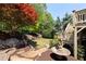 Backyard featuring a water feature, stone pathway, lush greenery, and access to an elevated wooden deck at 4675 Lakeway Pl, Alpharetta, GA 30005
