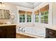Bathroom with a garden tub, bright windows, wood cabinets and stone tile at 4675 Lakeway Pl, Alpharetta, GA 30005
