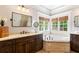 Bright bathroom features a soaking tub with mosaic accents and a dark-stained vanity at 4675 Lakeway Pl, Alpharetta, GA 30005