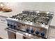 Close up of stainless steel oven range with blue knobs, light countertops, and mosaic backsplash at 4675 Lakeway Pl, Alpharetta, GA 30005