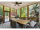 Covered porch with an outdoor dining area, featuring a large wooden table, comfortable seating, and views of the wooded landscape at 4675 Lakeway Pl, Alpharetta, GA 30005