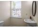Modern powder room with pedestal sink, oval mirror, and a window providing natural light at 2419 Ivey Crest Cir, Tucker, GA 30084