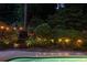 Tranquil backyard with a sparkling swimming pool, lush landscaping, and elegant string lights at 4228 Durham Cir, Stone Mountain, GA 30083