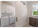 Bright laundry room with white cabinets, modern washer and dryer, wood-look flooring, and a barn door at 5635 Cherokee Trce, Cumming, GA 30041