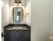 Stylish powder room with a black vanity, granite countertop, elegant mirror, and brass fixtures at 5635 Cherokee Trce, Cumming, GA 30041