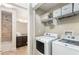 The laundry room features tile floors, a washer, a dryer, and wire rack shelving for storage at 200 River Vista Dr # 401, Atlanta, GA 30339