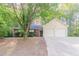 Charming home featuring a two-car garage, brick facade, and mature shade tree at 3856 Vine Stone Dr, Lithonia, GA 30038