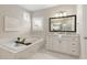 Bright bathroom featuring a soaking tub, double vanity, and white marble flooring at 5250 Briarstone Ridge Way, Alpharetta, GA 30022